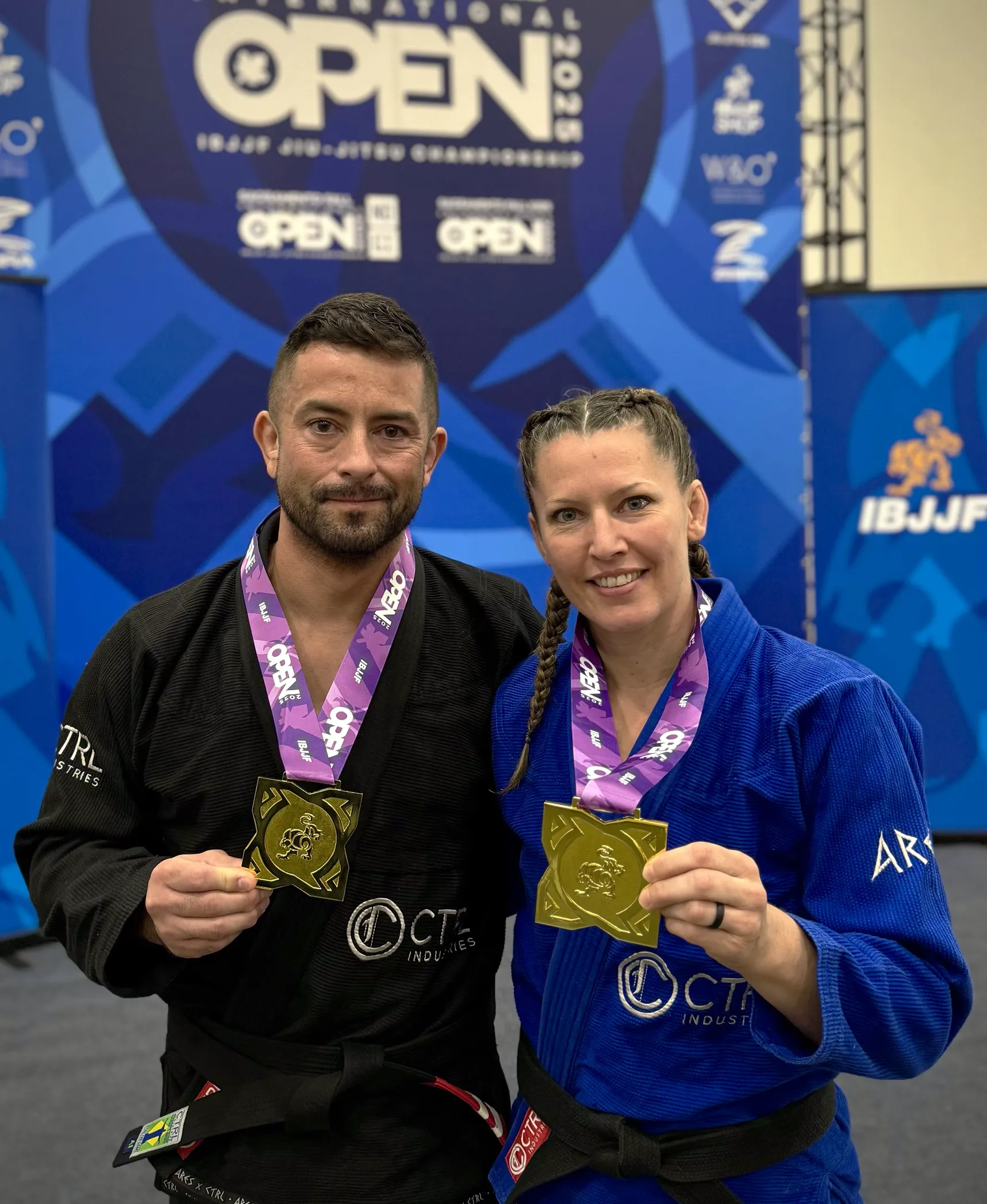 Jamie and Jeremy together, holding medals from 2025 IBJJ tournament